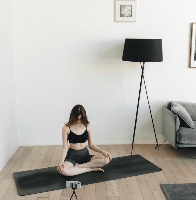 Woman in a peaceful yoga pose in a spacious, sunlit room.